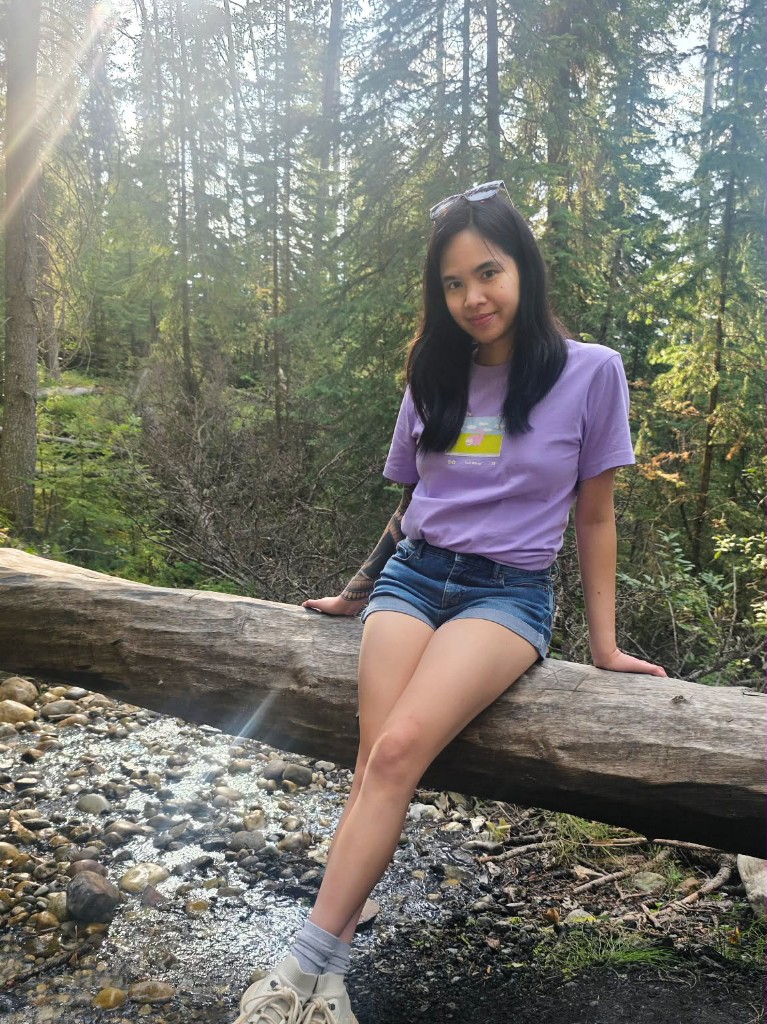 Stephanie sitting on a fallen log in a forest